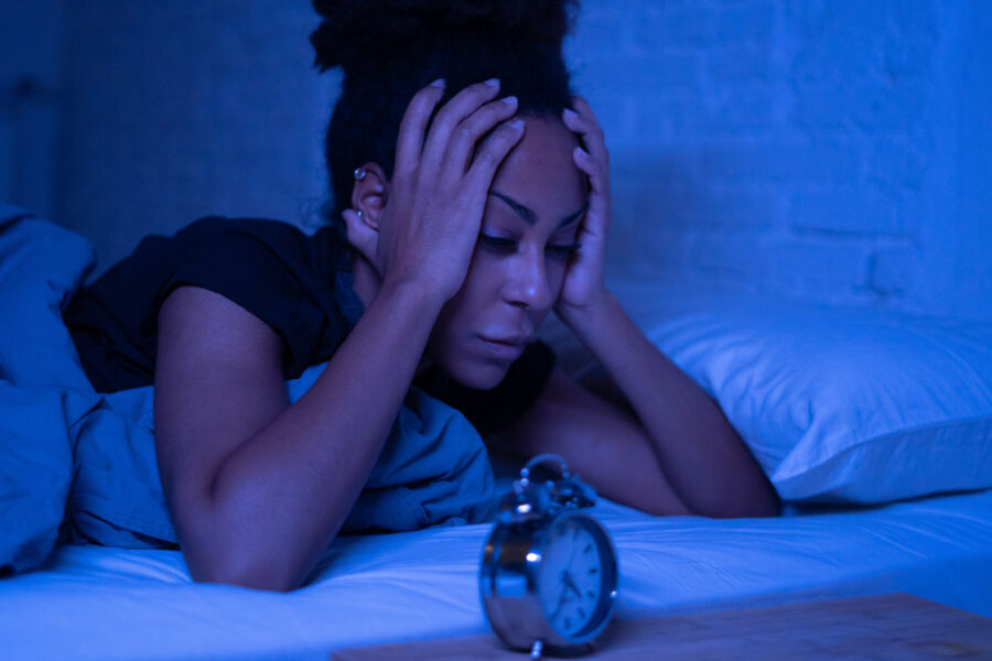 Woman holding head in hands in bed cant sleep