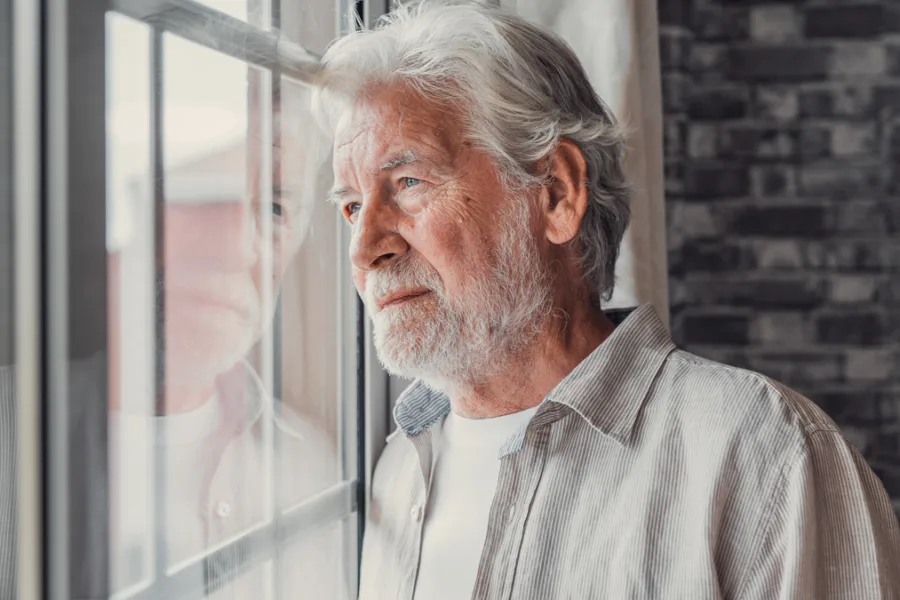 Senior man looking out window