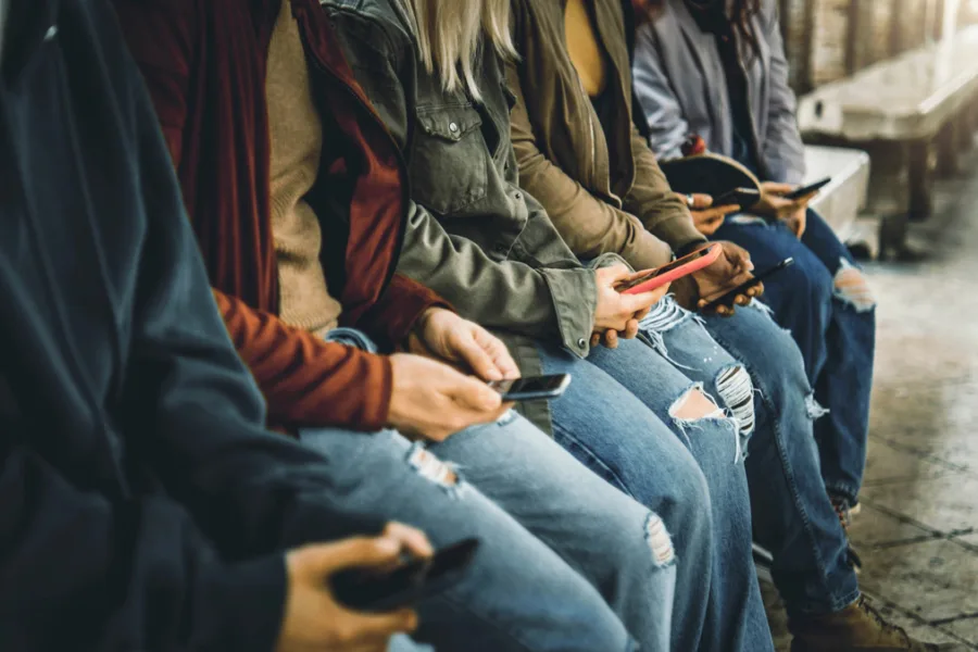 young people sitting next to each other all on their phone